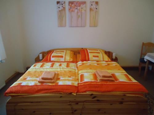 a bed with orange and white blankets on it at Pension Thaler Hof in Thale