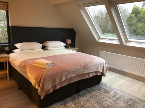 a bedroom with a large bed with two windows at Westport Coastal Lodge in Westport