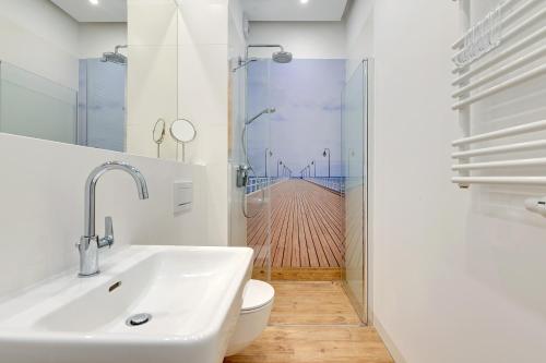 a bathroom with a sink and a toilet and a wooden floor at Apartment Long Gardens TriApart® in Gdańsk