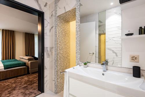 a bathroom with a tub, sink and mirror at The Gate Boutique Hotel Zürich in Glattbrugg