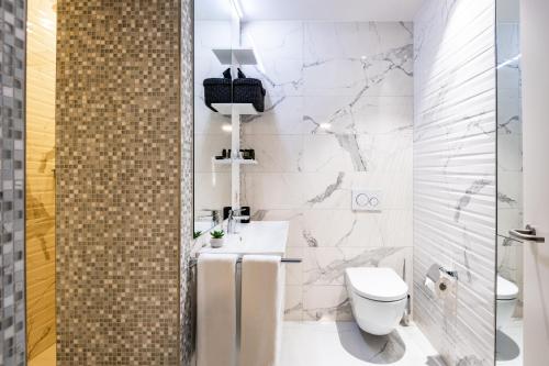 a white bathroom with a toilet and a sink at The Gate Boutique Hotel Zürich in Glattbrugg