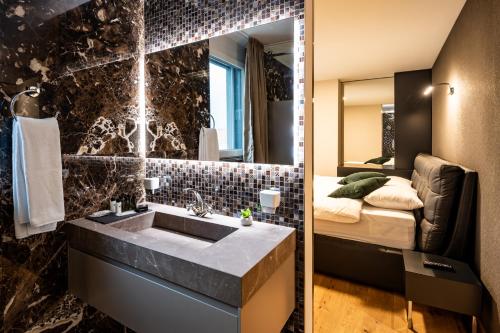a bathroom with a sink and a bedroom with a bed at The Gate Boutique Hotel Zürich in Glattbrugg