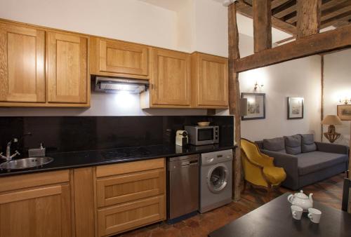 une cuisine avec des armoires en bois et un canapé dans une pièce dans l'établissement Gregoire Apartment, à Paris