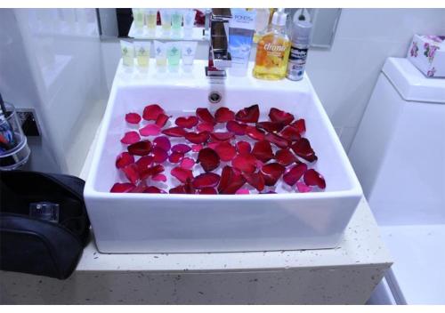 a sink filled with red rose petals on a counter at Dreams Grand in Hulhumale
