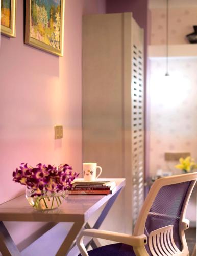 a table with a vase of flowers and a chair at Care Hotel Coast Collection in Sanya