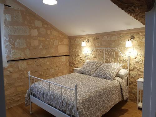 a bedroom with a bed and a stone wall at Domaine du chauvet in Sainte-Eulalie