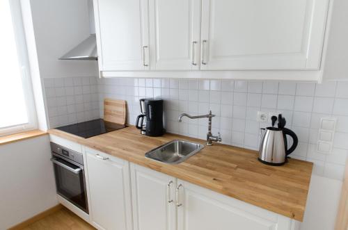 a kitchen with white cabinets and a sink at FeWo 2 Markranstädt in Markranstädt