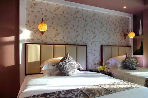 a bedroom with two beds and a wall with flowers at Care Hotel Coast Collection in Sanya