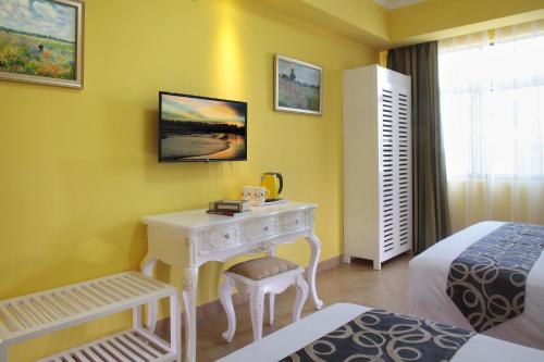 a bedroom with a white desk and a bed and a room at Care Hotel Coast Collection in Sanya