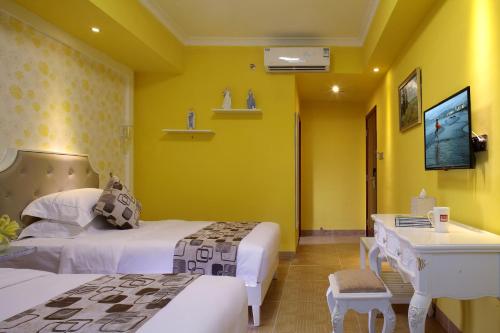 a room with two beds and a desk and a tv at Care Hotel Coast Collection in Sanya