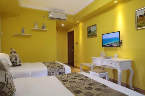 a hotel room with two beds and a tv at Care Hotel Coast Collection in Sanya