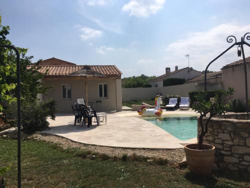 un patio trasero con piscina y una casa en Coquet 2 pièces au calme avec piscine (2/4 pers), en Fontvieille