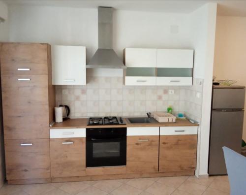a kitchen with wooden cabinets and a stove top oven at Apartment Luna in Tisno