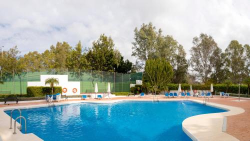 una gran piscina con sillas azules y árboles en 4 Bedroom apartment in Puerto Banus 150 meters from the beach, en Marbella