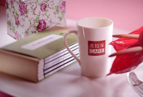 a coffee mug sitting next to a book on a table at Care Hotel Coast Collection in Sanya