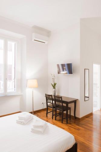 a room with two beds and a desk with a table at Piazza Cavour Suite in Rome