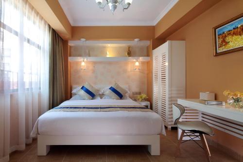 a bedroom with a white bed and a desk at Care Hotel Coast Collection in Sanya