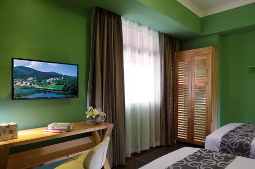 a green room with a bed and a desk and a window at Care Hotel Coast Collection in Sanya