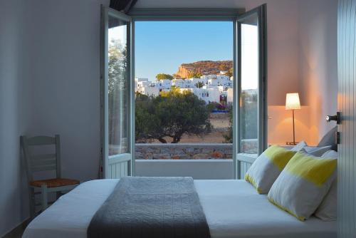 a bedroom with a bed and a large window at Anima Apartments in Chora Folegandros