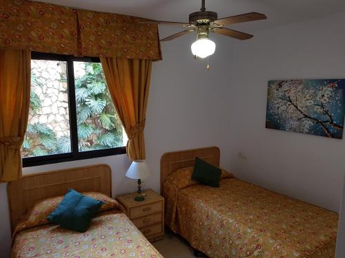 1 dormitorio con 2 camas y ventilador de techo en Torreoceano H4, en La Cala de Mijas