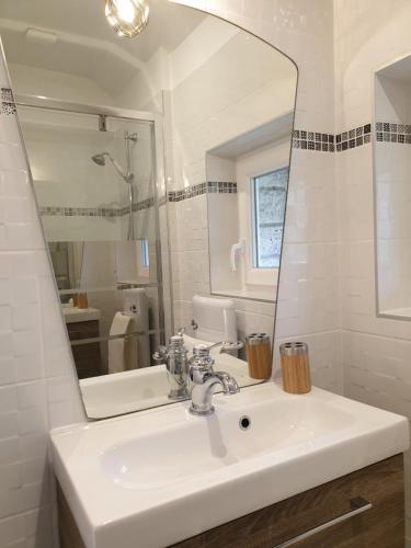 een witte badkamer met een wastafel en een spiegel bij Maison tout confort avec jardin - CHANTILLY, SENLIS, PARC ASTERIX, PARIS CDG in Avilly-Saint-Léonard