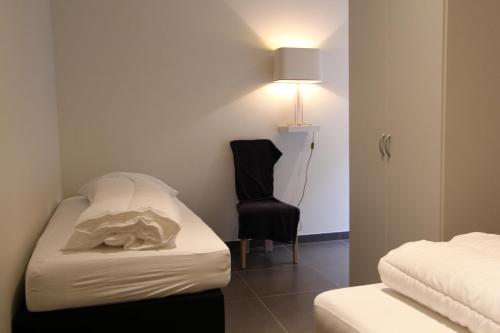 a room with a bed and a chair and a lamp at NUVOLA HOUSE in Zottegem