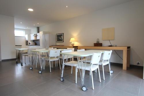 a room with tables and white chairs and a kitchen at NUVOLA HOUSE in Zottegem