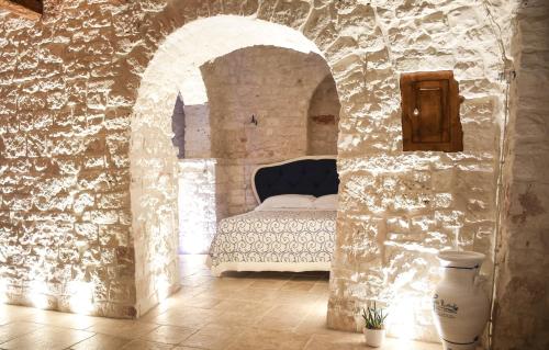 um quarto com uma cama numa parede de pedra em Trulli e Puglia Luxury Suite em Alberobello