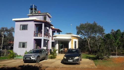 two cars parked in front of a house with a lighthouse at Flat da Pousada Avalon (Bolinha) in Alto Paraíso de Goiás