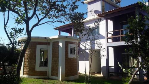 a white house with a tree in front of it at Flat da Pousada Avalon (Bolinha) in Alto Paraíso de Goiás