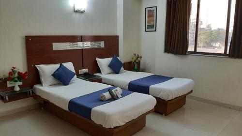 a hotel room with two beds with blue and white pillows at Hotel Happiness in Surat