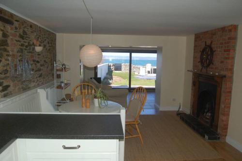 a kitchen with a table and chairs and a fireplace at Splash Cottage, Bangor, Co Down in Bangor