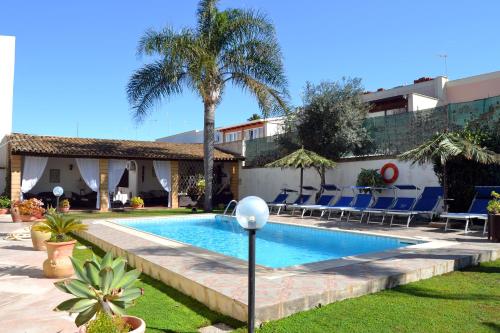 una piscina con sedie blu e una palma di Brunelli Residence a Mazara del Vallo