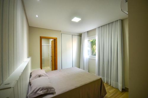 1 dormitorio con cama y ventana en 1078 - Apartamento com vista para o mar em Bombinhas, en Bombinhas