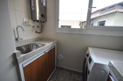 una pequeña cocina con fregadero y ventana en 1079 - Apartamento com vista para o mar em Bombinhas, en Bombinhas