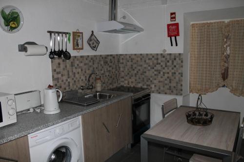 a kitchen with a sink and a washing machine at Casa da Avó Rita in São Pedro do Corval