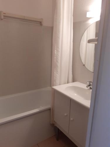 a white bathroom with a sink and a bath tub at Studio cabine Thalacap Vue mer in Banyuls-sur-Mer