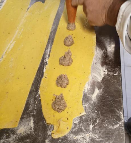 a personeading a piece of dough with three meatballs at Tenuta San Marcello in San Marcello