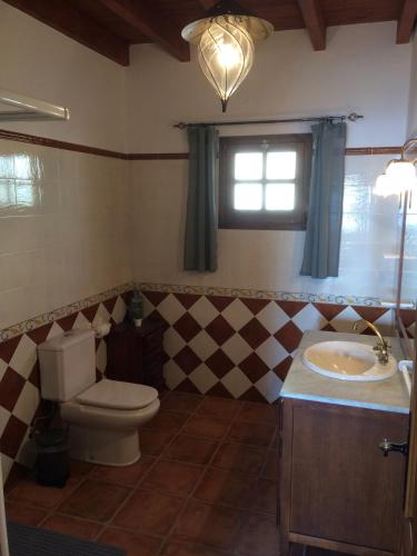 Un baño con inodoro, lavabo y ventana. en Casablanca, en Iznate