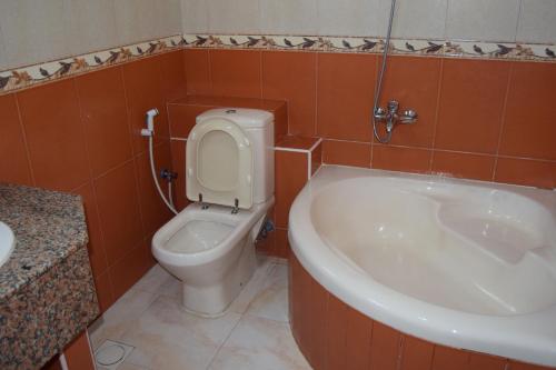 a bathroom with a toilet and a sink and a tub at Hotel Summersands in Seeb