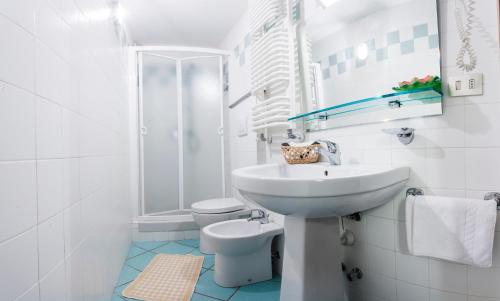 bagno bianco con lavandino e servizi igienici di Hotel Biancaneve a Sestriere