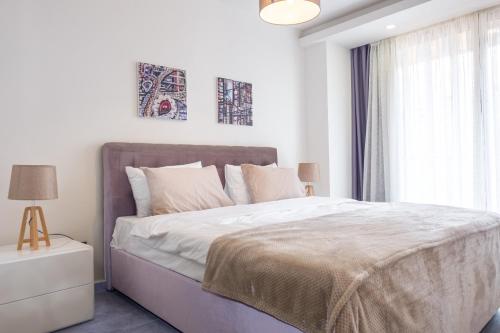 a white bedroom with a large bed and a window at Deluxe Apt w/ Rooftop Pool in The Heart of Kyrenia in Kyrenia