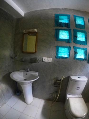 a bathroom with a sink and a toilet and blue lights at Charlotte's Coral Breeze - A Colonial Seaside Bungalow in Hikkaduwa