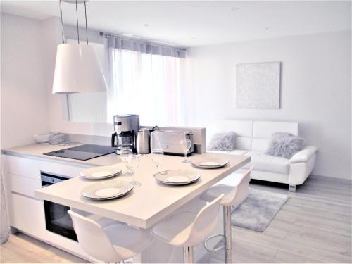 une cuisine blanche avec une table et des chaises dans une pièce dans l'établissement Le White Cosy à 5 minutes du Lac avec parking privatif gratuit, à Annecy