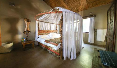 a bedroom with a canopy bed in a room at Norman Carr Cottage in Monkey Bay