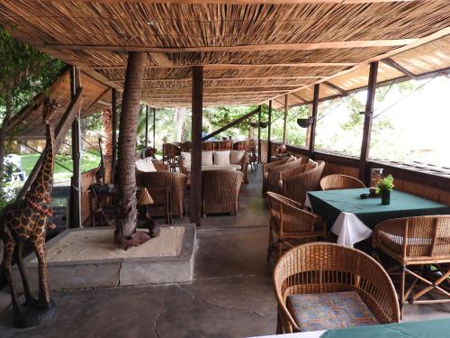 un restaurante con una jirafa de pie bajo un techo de madera en Norman Carr Cottage en Monkey Bay