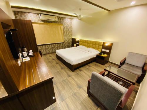 Habitación de hotel con cama y silla en Saluja Residency en Siliguri