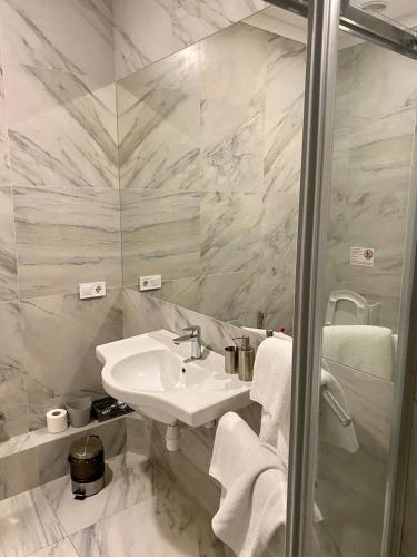 a white bathroom with a sink and a shower at ArkPalmira in Odesa