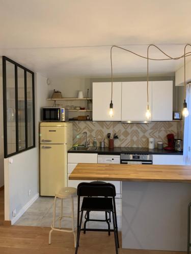 a kitchen with white cabinets and a wooden counter top at T2 cosy 70s in Avignon