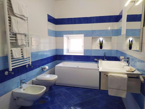 uma casa de banho azul e branca com uma banheira, um WC e um lavatório. em Via Paradiso em Amalfi